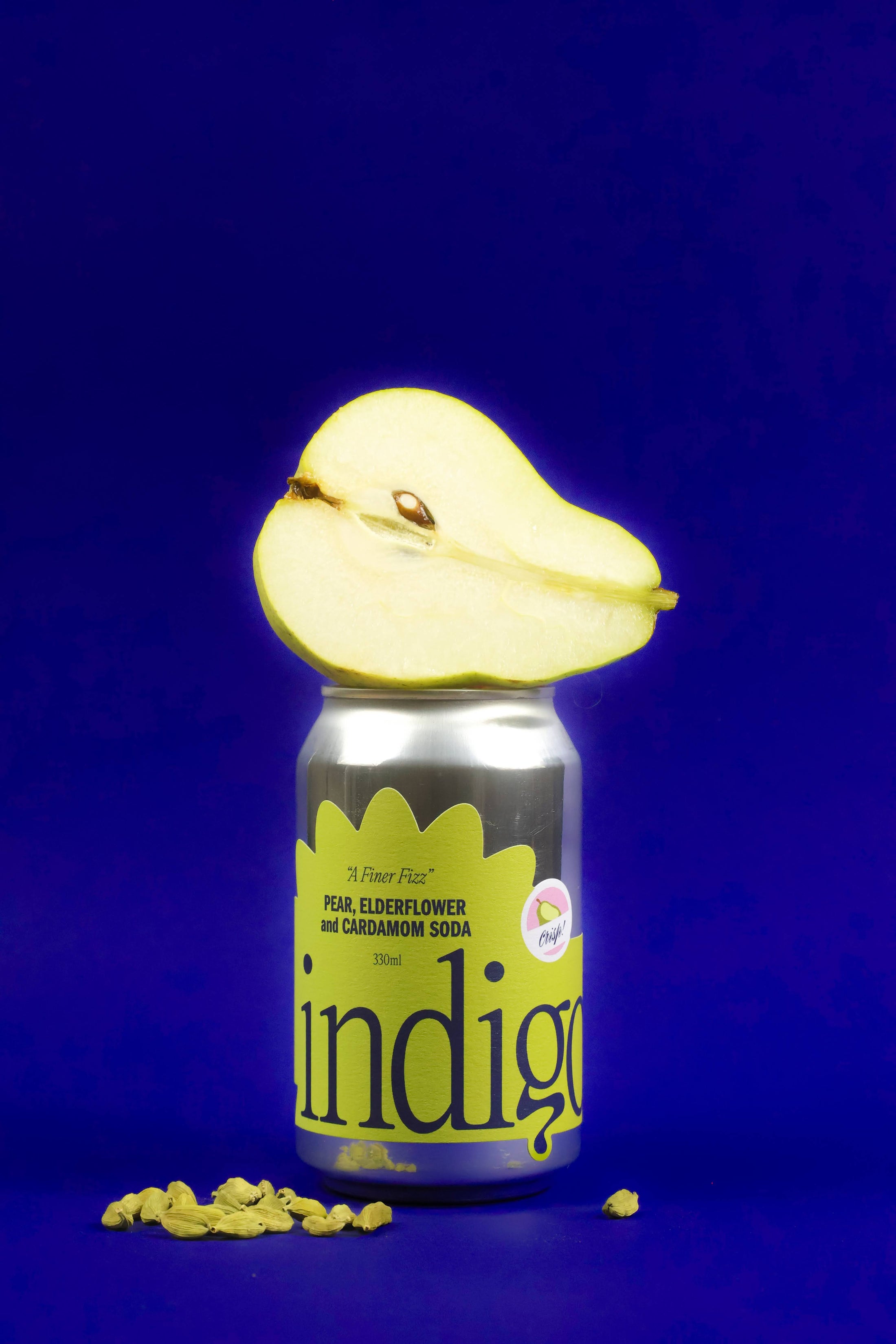 A can of Indigo soda with a slice of pear attached to it, set against a blue background.