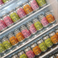 Load image into Gallery viewer, A fridge stocked with indigo soda cans in all three flavours: Raspberry, Habanero and Lime (pink), Mandarin, Bergamot and Lemon Myrtle (orange) and Pear, Elderflower and Cardamom (green)
