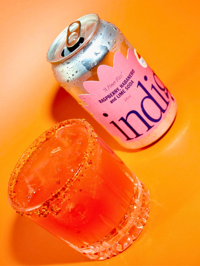 The Second Date from above – pink and icy in a Tajín-rimmed glass, next to an open, chilled can of indigo Raspberry, Habanero & Lime soda