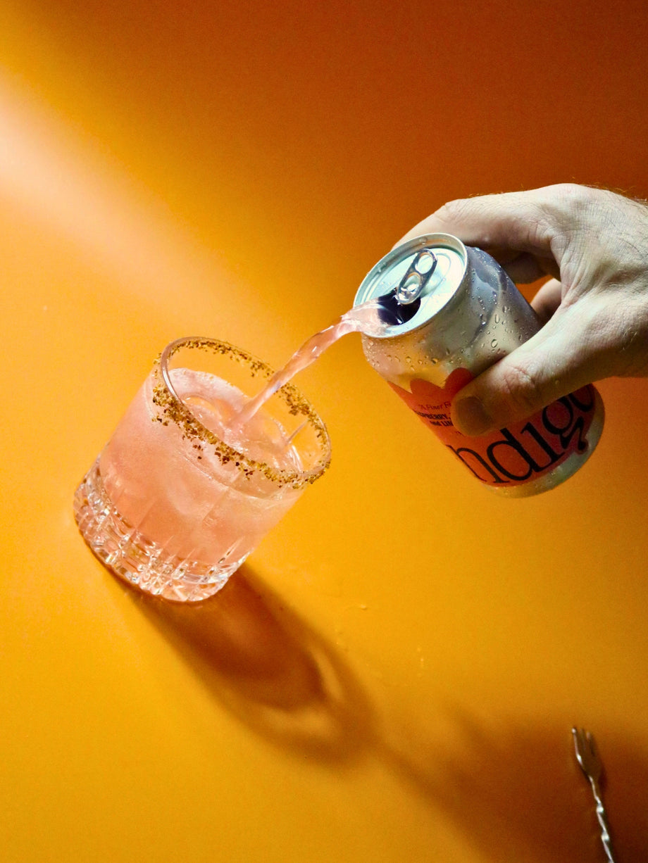 Topping up a Tajín-rimmed glass of ice and tequila with indigo Raspberry, Habanero & Lime soda, a bar spoon at the ready